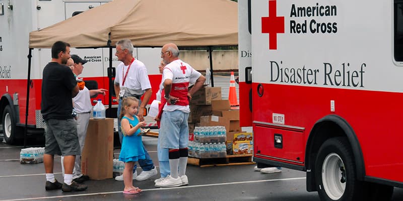 Two American Red Cross volunteers giving aid and relief to a family of three