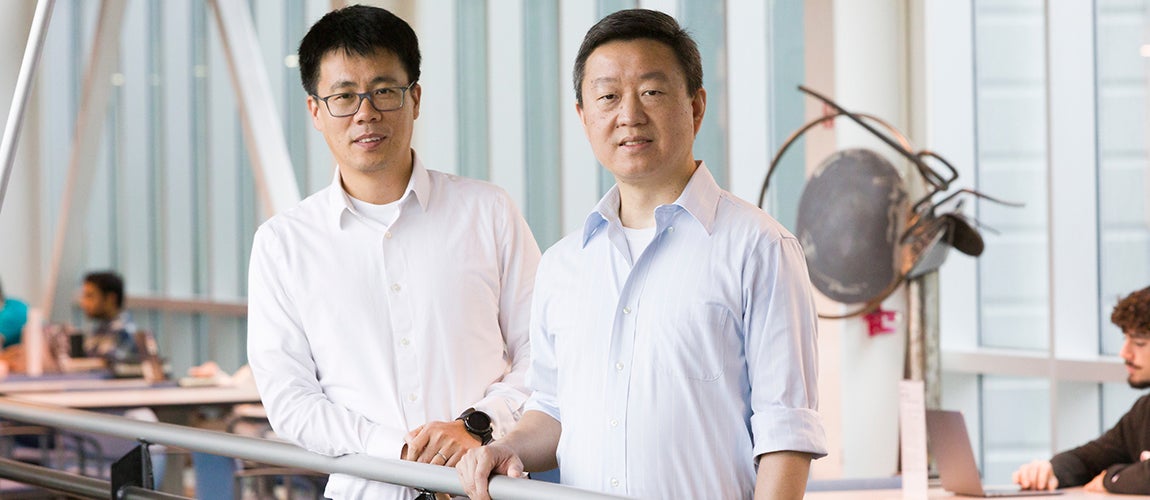 two men one in glasses standing by railing in building