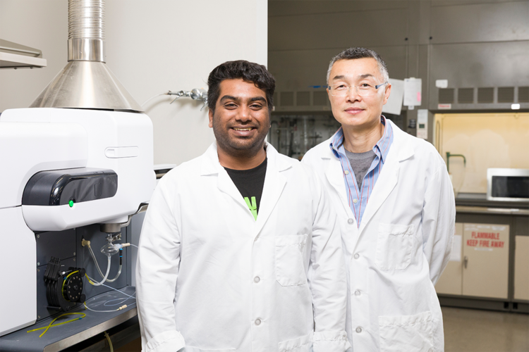 two men in lab coats smiling and standing in lab
