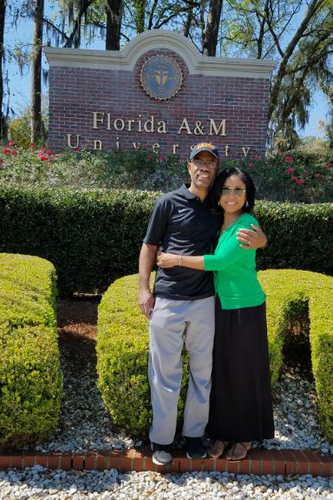 man and woman embracing in front of FAMU sign