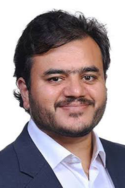 man in blue suit white shirt with beard smiling at camera