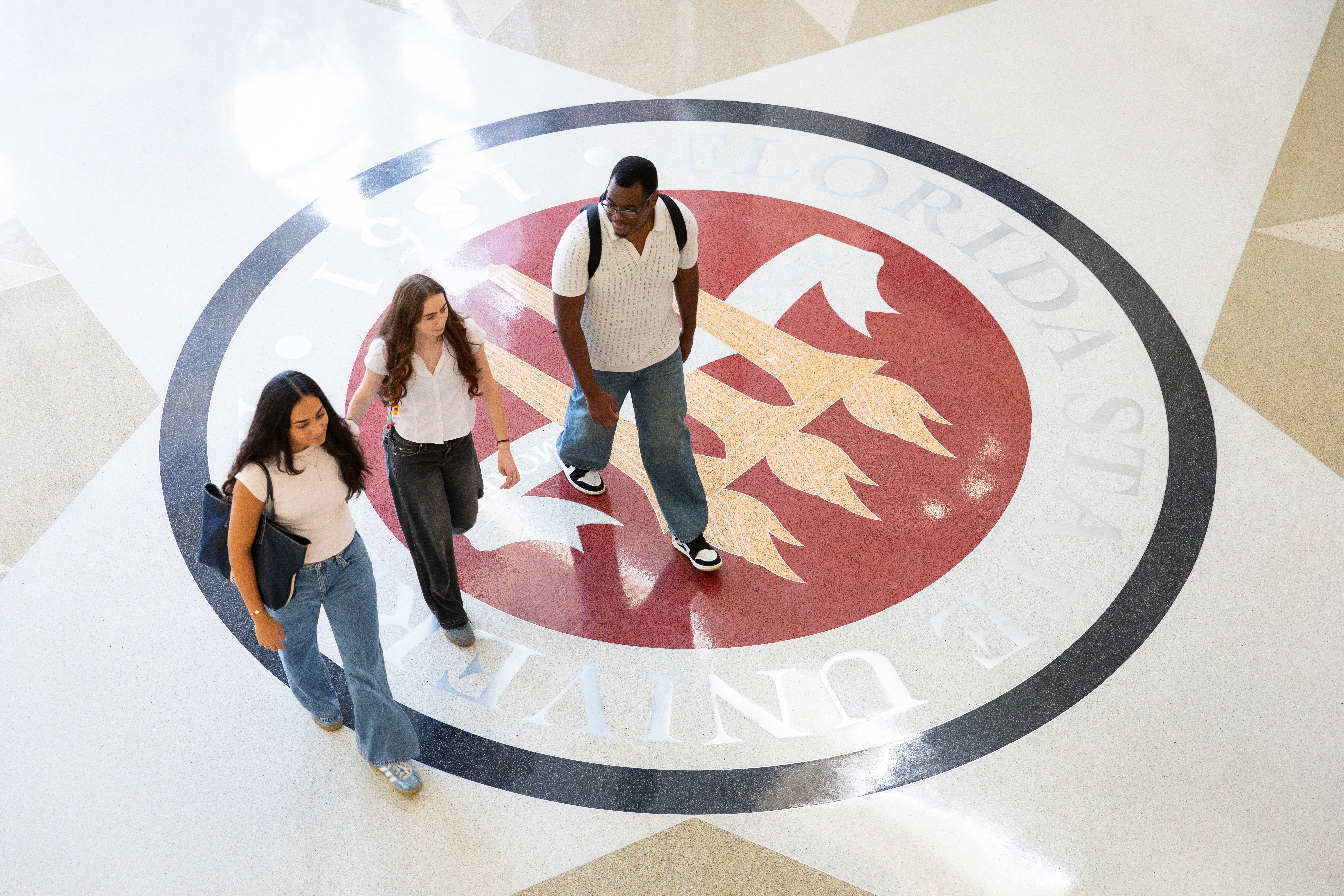 Students walking over the FSU seal of tile.