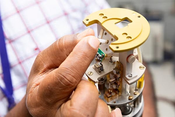 Rams Ph.D. loads a sample into a probe in a lab.