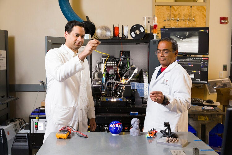 Jamel Ali, Ph.D., (L) and Subramanian Ramakrishnan, Ph.D., pose with the nScrypt 3D printer at the High-Performance Materials Institute (HPMI) of the Materials Research Building (MRB) at FAMU-FSU College of Engineering in Tallahassee, Florida on March 27, 2025.