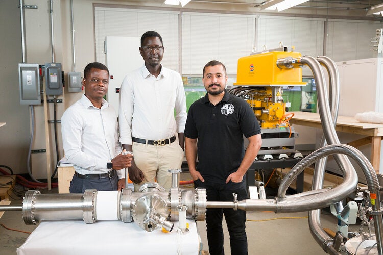 (L-R): David Sackey, Yai Pioth Yai Deng, and Muhammad Tahir Mehmood Khan Niazi pose with cryogenic equipment in the Center for Advanced Power Systems (CAPS) in Tallahassee, Florida on June 16, 2025.
