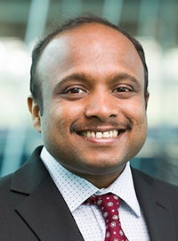 man in dark suit and red tie smiling at camera