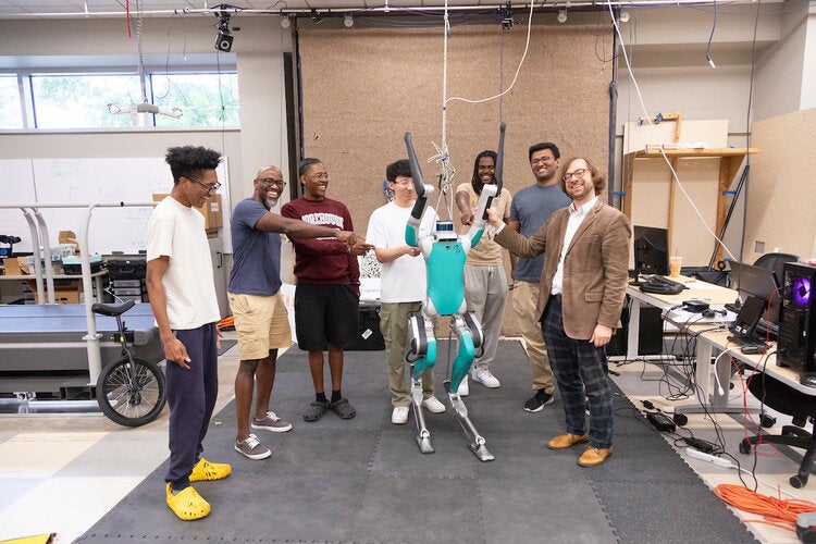 (L-R): Rasheed Jeheeb, Morehouse College professor Dr. Dwayne Joseph, Winston Doss, Tianze Wang, Kylin Davis, Vivek Annem, and Dr. Christian Hubicki in Dr. Hubicki's lab with "Digit" the robot in the Center for Intelligent, Systems, Control, and Robotics (CISCOR) in the Aero-propulsion, Mechatronics, and Energy Center (AME) of FAMU-FSU College of Engineering in Tallahassee, Florida on June 27, 2024.