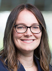 woman smiling with brown hair and glasses