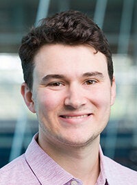 man with short hair and pink shirt smiling