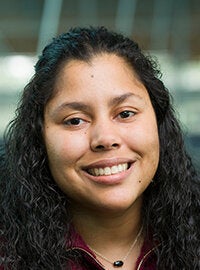 woman with long black curly hair smiling