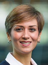 smiling woman in white shirt and blue suit with short hair and earrings