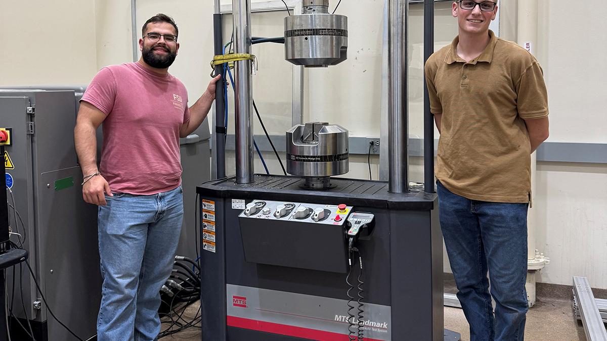 photo of two men standing in front of machine in lab