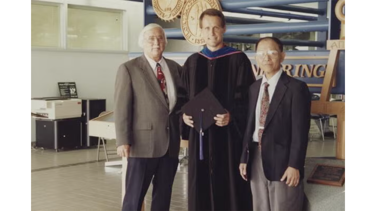 photo of two men and one graduate in robe standing together