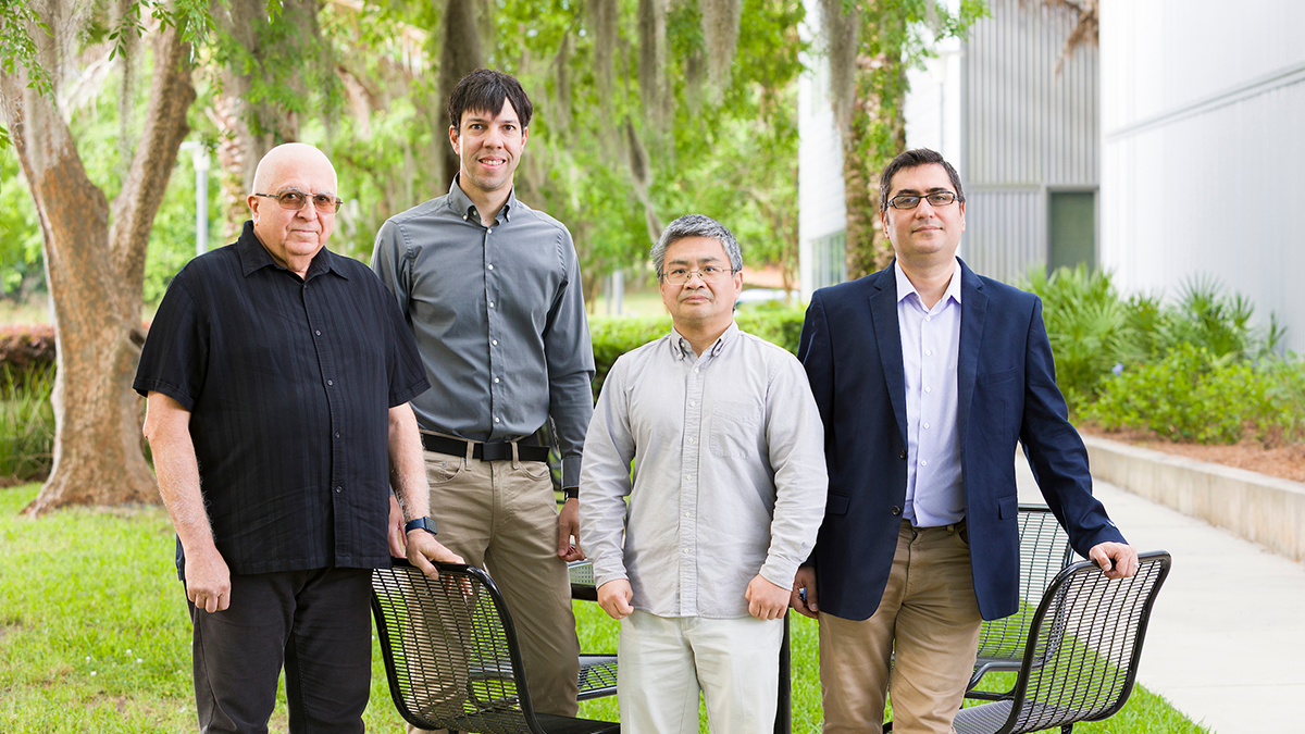 photo of four men standing in front of a table outside