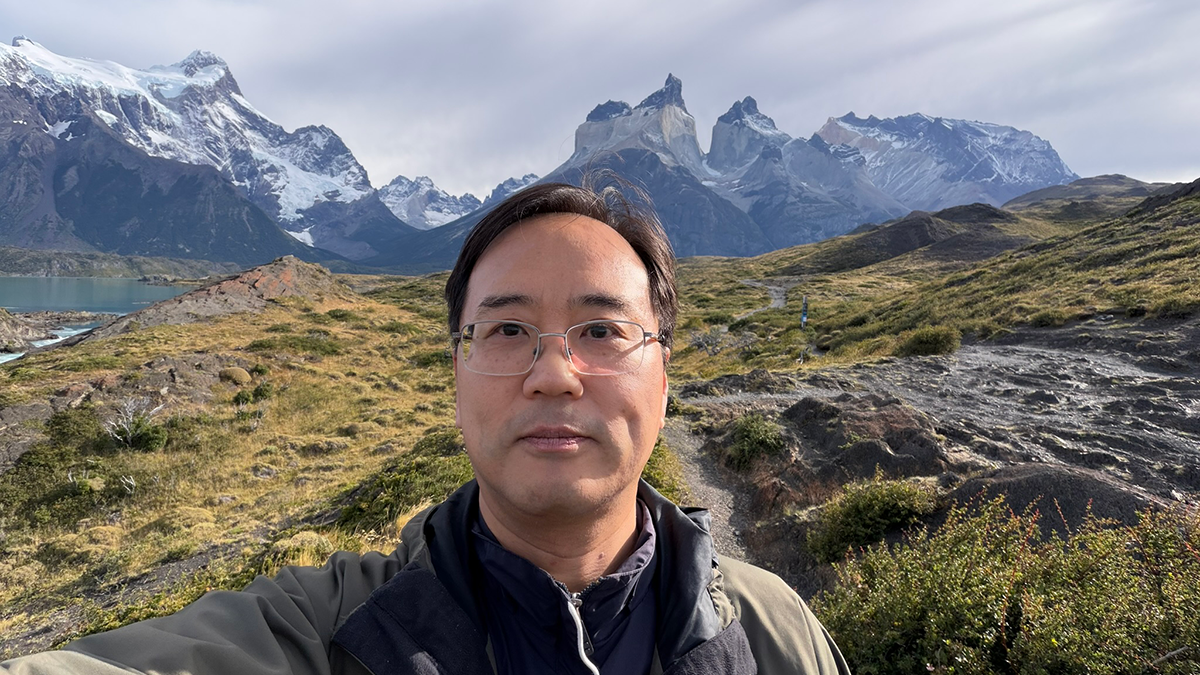 photo of many with glasses in jacket standing in front of chilean mountains and water