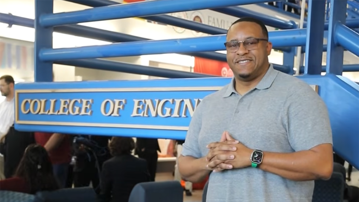 photo of man in glasses and gray polo shirt with hands clasped at chest in the college of engineering