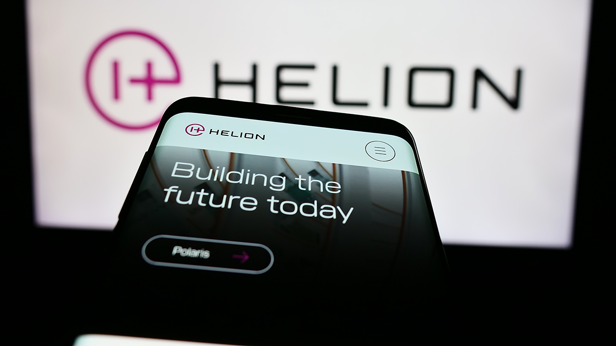 Photo of Mobile phone with website of US fusion power company Helion Energy Inc. in front of business logo. Focus on top-left of phone display
