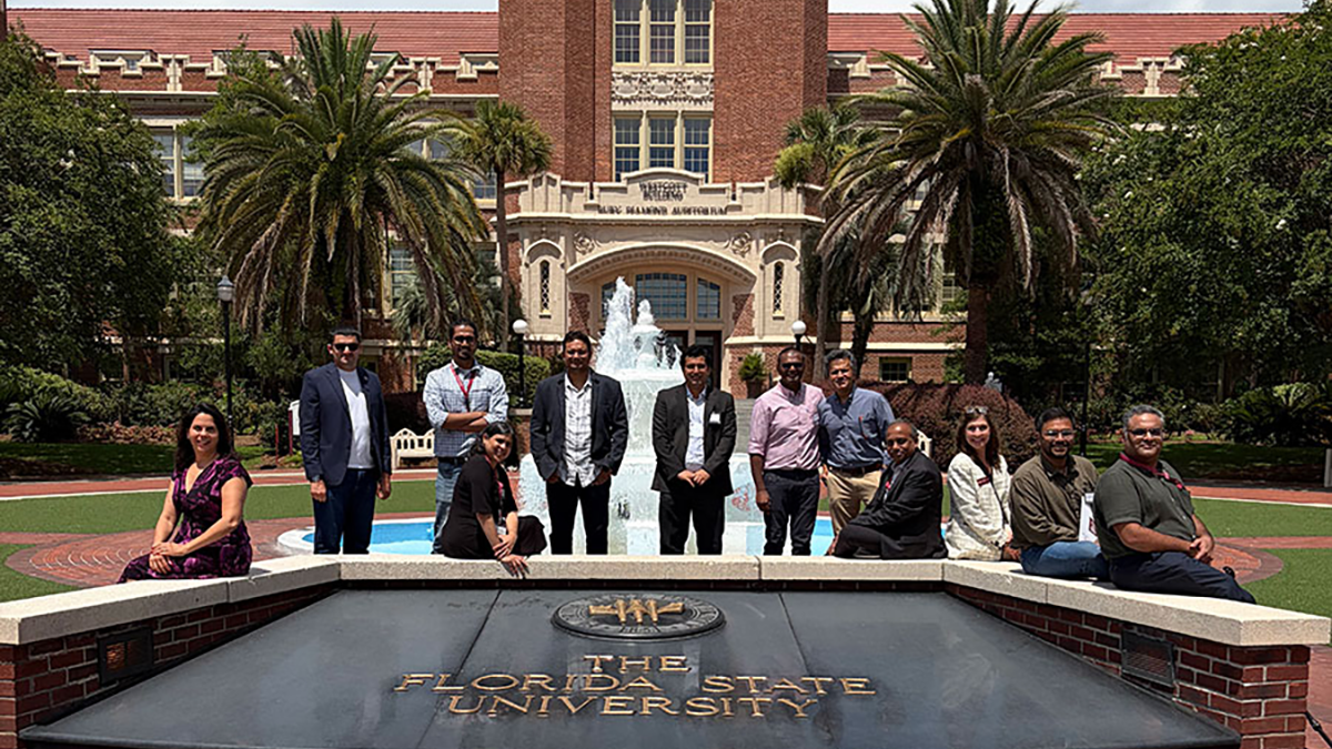 group of people standing in front of building, fountain with words Florida State University in front of them