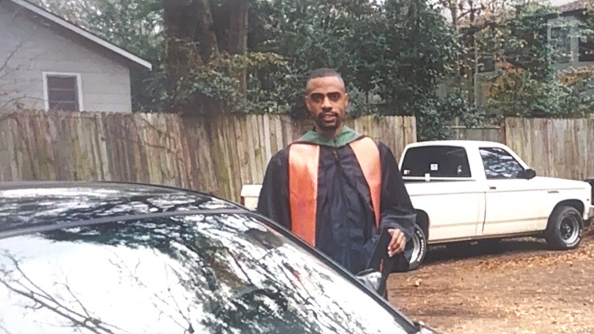 man in graduation regalia in front of car old image