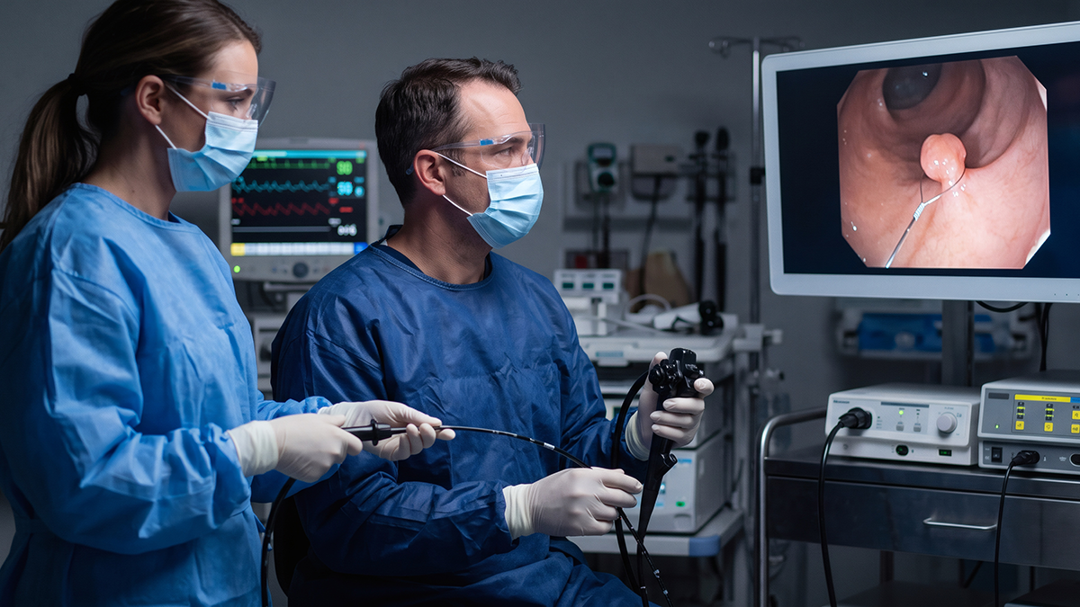 two sterile surgeons in blue gowns watching high definition video monitor during endoscopy operation