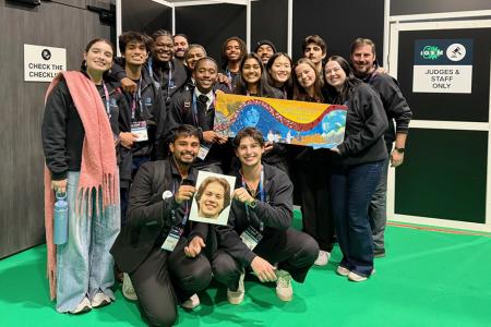 photo of students in black sweatsuits holding photo and banner