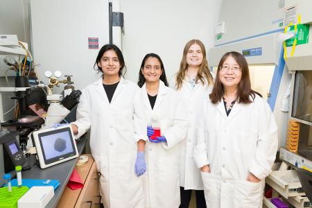 photo of group of females in lab coats standing in lab