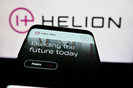 Photo of Mobile phone with website of US fusion power company Helion Energy Inc. in front of business logo. Focus on top-left of phone display