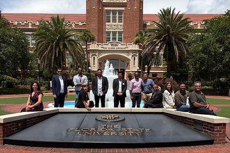 group of people standing in front of building, fountain with words Florida State University in front of them