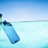 photo of two plastic bottles floating in water with blue sky