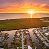 Sunset aerial view of Punta Gorda wealthy neighborhood. Expensive residential homes along canals reflect warm evening sky.