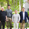 photo of four men standing in front of a table outside