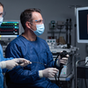two sterile surgeons in blue gowns watching high definition video monitor during endoscopy operation