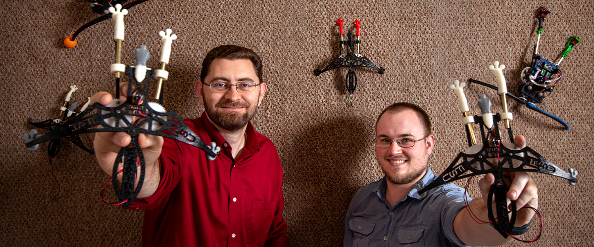 Dr. Jonathan Clark and graduate student Jason Brown show off small robots with gecko-like feet that climb and stick to a wall.