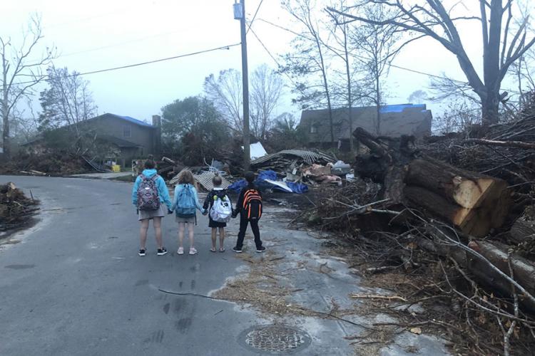 4 children holding hands while looking at debris
