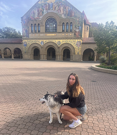 Photo of ashley david with dog in front of Stanford’s memorial church. 