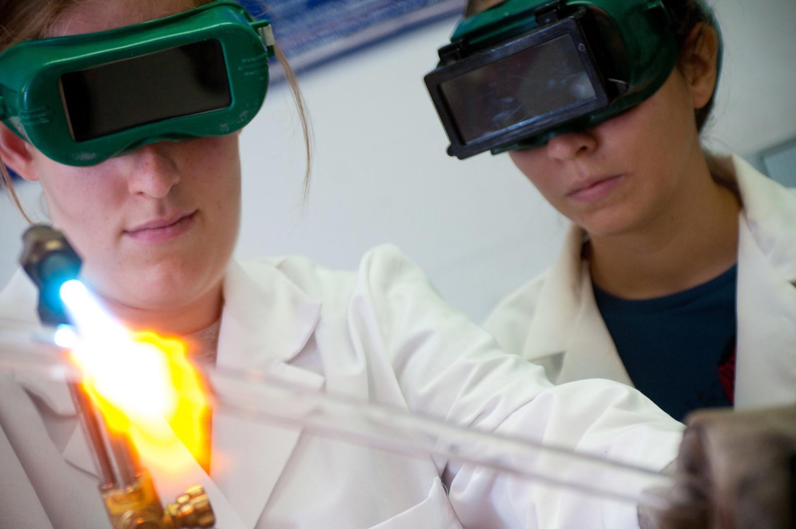 Two female students working in a lab facility with a blowtorch 