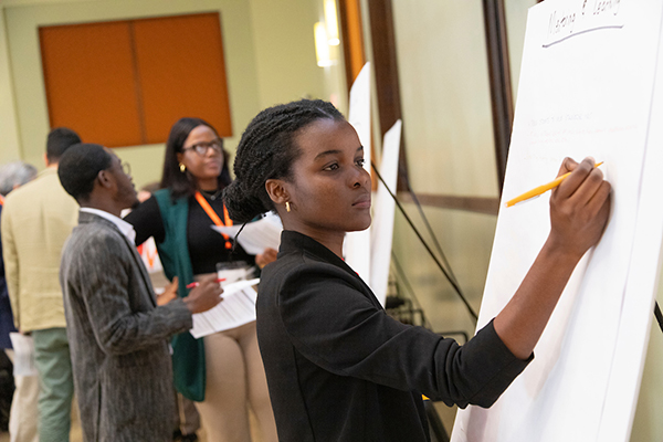 closeup photo of black female college student writing on a white board at conference