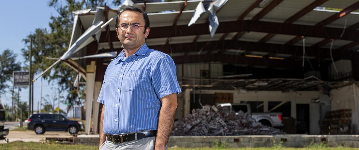 Ozguven in front of destroyed building