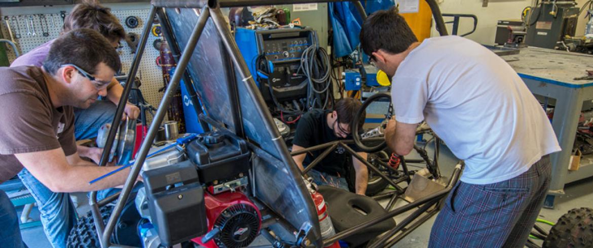 Four students working on a project car