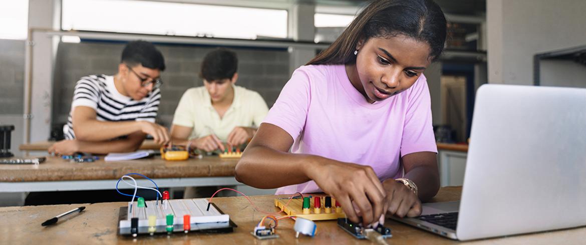 photo of young black girl working on a computer circuit board