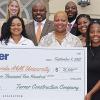 13 people stand for a photo op in front of a $72.5k FAMU Signs Agreement with Turner Construction Company