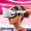 photo of teen girl wearing VR glasses in front of a large video display