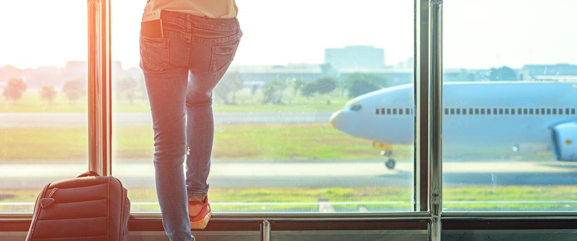 photo of woman watching airliner on runway