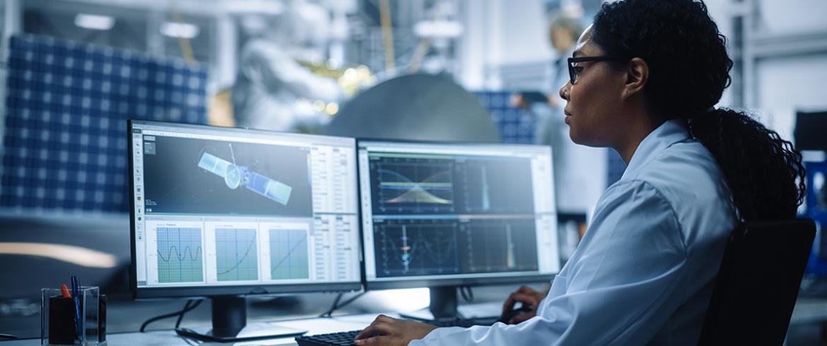 photo of black aerospace engineer at computer looking at satellite design