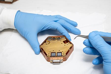 photo of two hands with tweezers over octagon-shaped disc