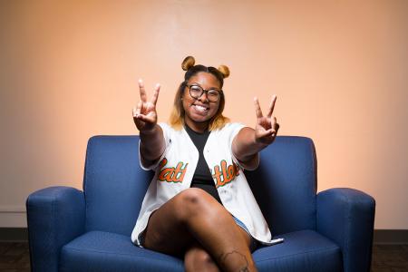 photo of nia britton on blue couch holding up two peace signs smiling
