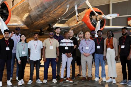 photo of group of students in front of antique silver airplanes