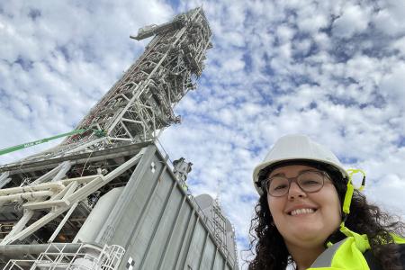 gabrielle mayans in front of large metal crane