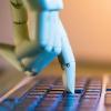 photo of robotic hand pushing a computer key